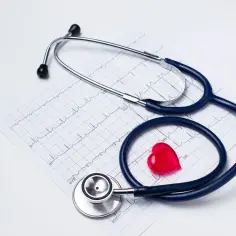 Stetoskop na EKG i czerwone serce. Zastanawiasz się, ile kosztuje ubezpieczenie zdrowotne?