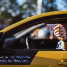 Kierowca pokazuje prawo jazdy, odpowiadając na pytanie, czy trzeba mieć przy sobie dokument.