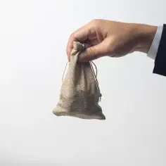 Dłoń w garniturze trzyma woreczek. Czy to odpowiedź na pytanie, ile wynosi zasiłek dla bezrobotnych?