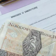 Wniosek o emeryturę ZUS z banknotami 200 zł. Dokumenty i pieniądze sugerują ponowne przeliczenie emerytury ze względu na długość życia.