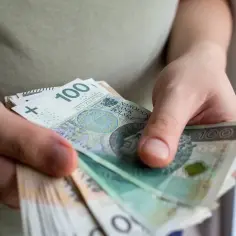 Dłonie liczą banknoty 100 zł. To może być pomoc de minimis dla przedsiębiorcy.