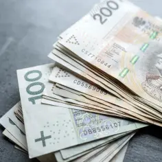 Stos banknotów 100 i 200 zł, symbolizujących oszczędności na wcześniejszą emeryturę.