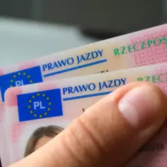 Dwie polskie karty prawa jazdy, widoczne z bliska. Na kartach widnieje napis "Prawo jazdy" i godło Polski. Różne kategorie prawa jazdy są dostępne dla kierowców.