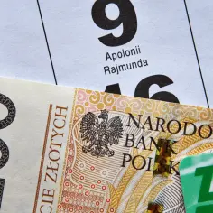Kalendarz z datami i nazwami, banknot 200 zł i zielona karta ZUS. Od czego zależy termin wypłaty emerytury?