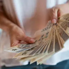 Dłonie trzymają wachlarz banknotów 200 zł. To może być nagroda jubileuszowa za lata pracy.