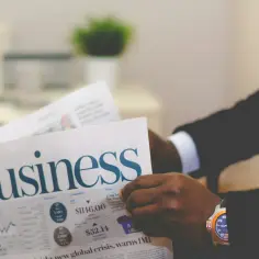 Biznesmen czyta gazetę "Business". Zastanawia się, krs co to jest i jak wpływa na jego inwestycje.