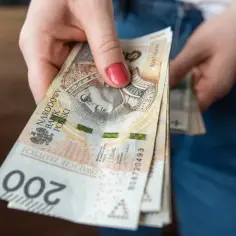 Dłoń trzyma plik banknotów 200 zł. To może być część wypłaty, np. 6000 brutto.