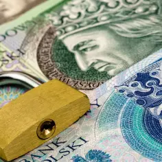 Złoty z kłódką symbolizuje bezpieczeństwo finansowe i wadium. Polskie banknoty z wizerunkami władców są zabezpieczone.