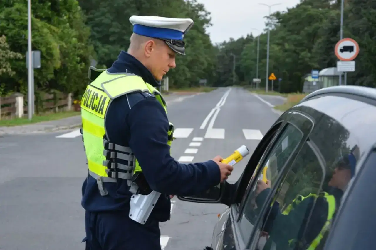 Policjant kontroluje kierowcę alkomatem. Jazda pod wpływem alkoholu to poważne wykroczenie.