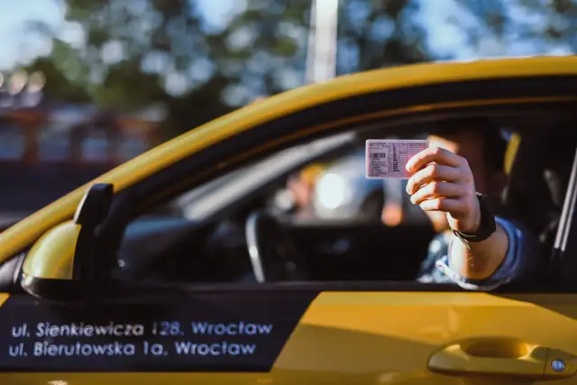 Kierowca pokazuje prawo jazdy, odpowiadając na pytanie, czy trzeba mieć przy sobie dokument.
